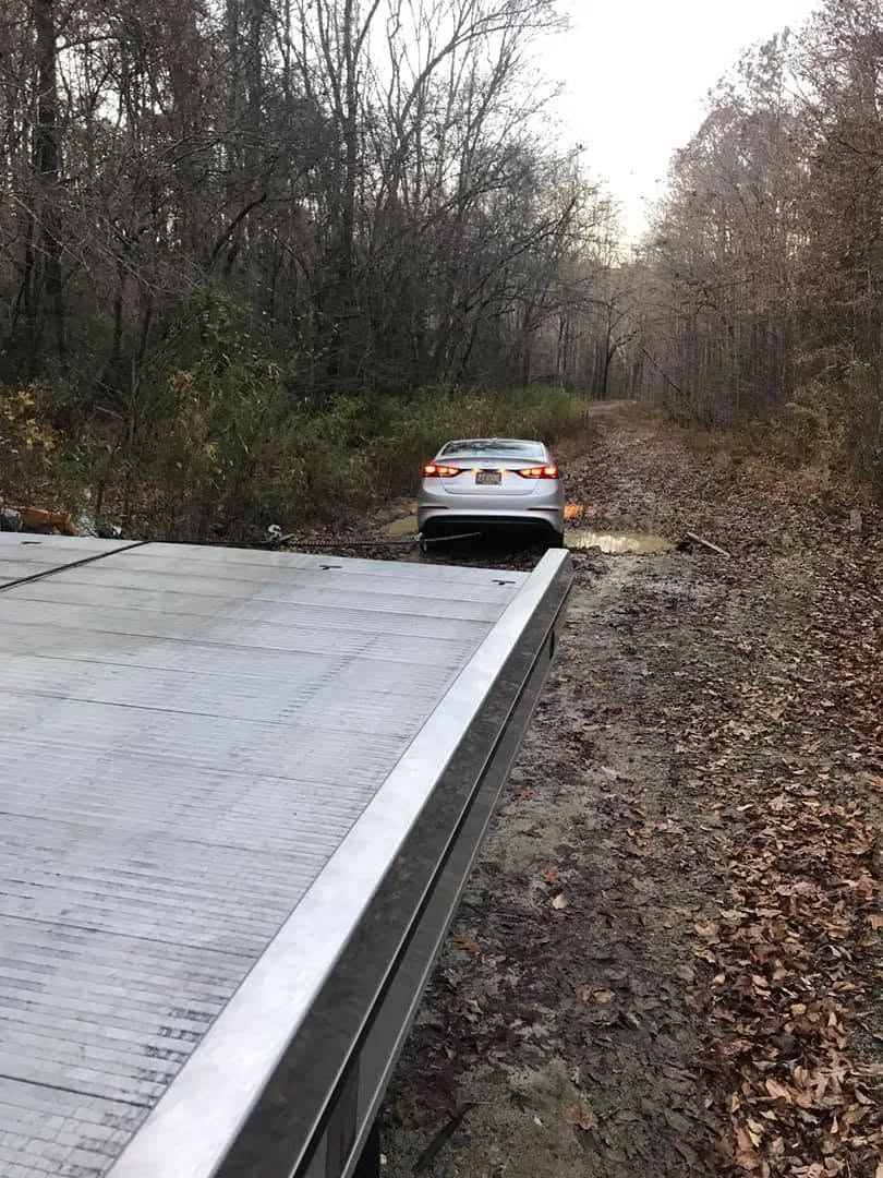 Sedan stuck on a muddy trail with the winch cable attached